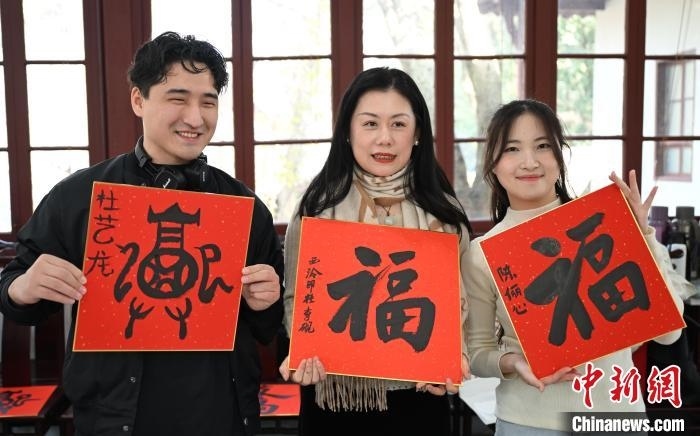 1月20日，外籍留學(xué)生和西泠印社社員李硯(中)展示各自創(chuàng)作的福貼。當(dāng)日，來(lái)自巴西、馬來(lái)西亞、加納、哈薩克斯坦的外籍留學(xué)生在浙江杭州西泠印社體驗(yàn)福貼、春聯(lián)和篆刻，感受古老的中國(guó)傳統(tǒng)文化。中新社記者 王剛 攝
