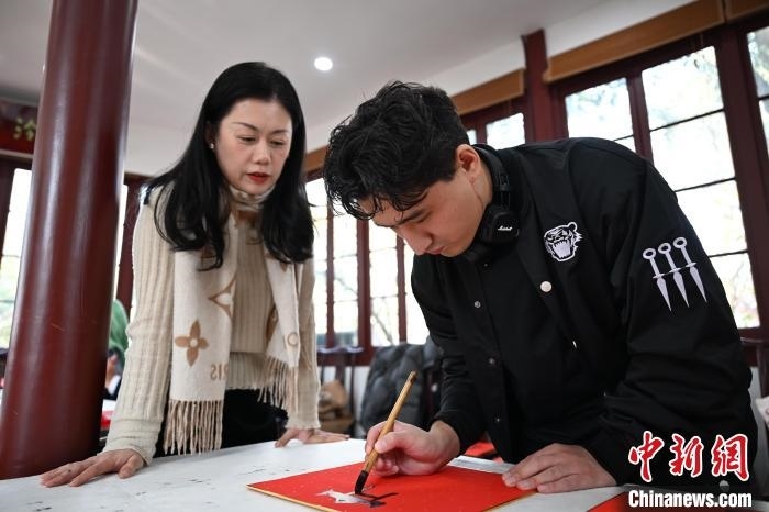1月20日，外籍留學(xué)生在西泠印社社員李硯指導(dǎo)下寫福。當(dāng)日，來(lái)自巴西、馬來(lái)西亞、加納、哈薩克斯坦的外籍留學(xué)生在浙江杭州西泠印社體驗(yàn)福貼、春聯(lián)和篆刻，感受古老的中國(guó)傳統(tǒng)文化。中新社記者 王剛 攝