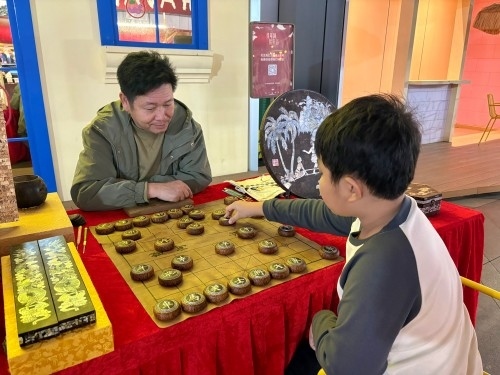 柯秋楓與市民下椰雕象棋。人民網(wǎng) 陳葉欣攝