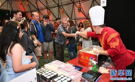 圖為游客在燈節(jié)現(xiàn)場購買小吃。（圖片由奧克蘭中國文化中心提供）