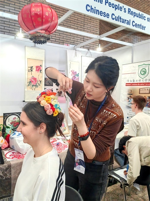 展覽正值羅馬尼亞迎春花節(jié)，國(guó)際中文教師志愿者潘婧穎向游客們介紹了國(guó)家非物質(zhì)文化遺產(chǎn)——福建泉州的簪花文化。布加勒斯特大學(xué)孔子學(xué)院供圖。