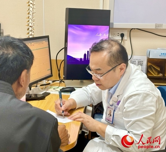 路桂軍接診時(shí)為患者寫下用藥提示。人民網(wǎng)記者 金慧慧攝