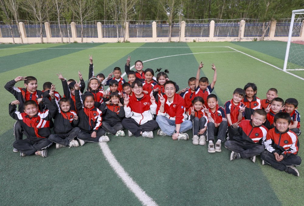 4月23日，在新疆克州阿圖什市哈拉峻鄉(xiāng)謝依特小學(xué)，支教教師王俊文（中左）、李軻凡（中右）和學(xué)生在一起。
