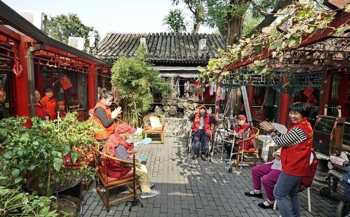 2024年10月12日，鐘樓灣胡同的老年人在社區(qū)內(nèi)的四合院養(yǎng)老驛站休閑。2017年起，北京市先后開(kāi)展了兩輪背街小巷環(huán)境整治提升行動(dòng)，完整保留了中軸線生活建筑群的歷史信息，并根據(jù)居民的生活和居住方式進(jìn)行適配化的更新和改造，極大地改善了生活環(huán)境。2023年鐘樓灣胡同被評(píng)為“北京最美街巷”。