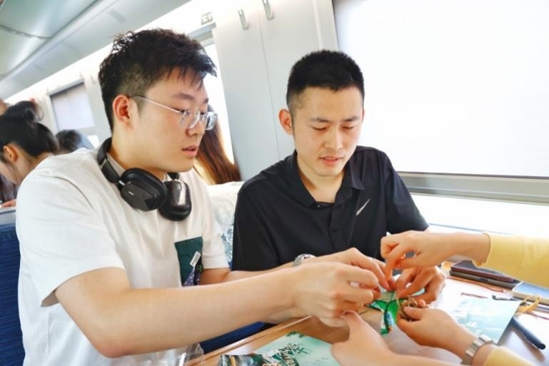 G232次旅客親手制作端午荷包和五彩繩。王磊攝